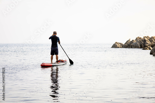 Photography Senior man paddle surf on the beach
