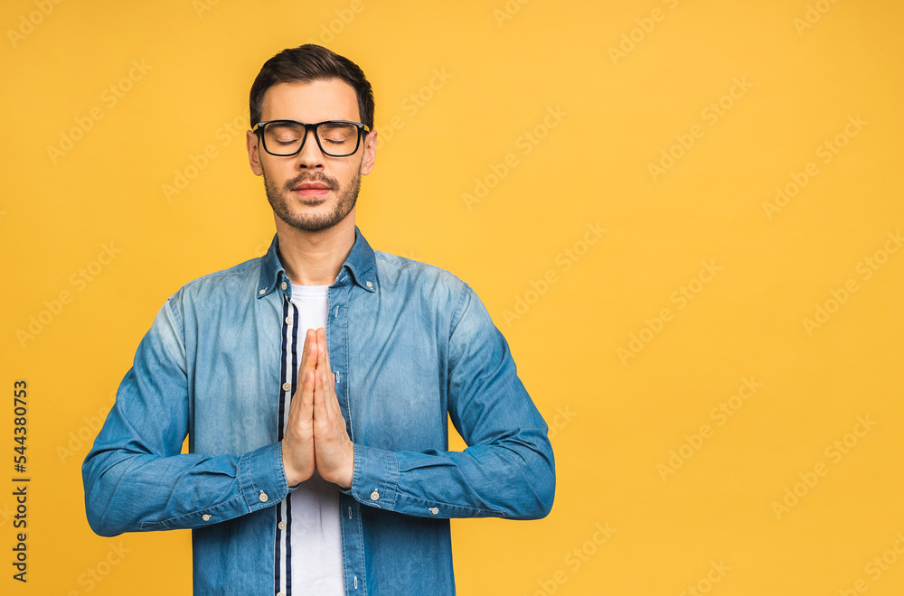 Fototapeta premium Concentrated relaxed person, standing with closed eyes, having relaxation while meditating, trying to find balance and harmony. Yoga and meditation concept. Isolated over yellow background.