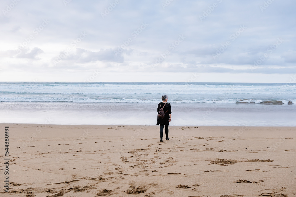 Female pensioner walking towards sea Female pensioner walking towards sea