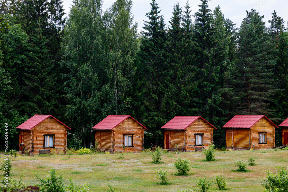 Small wooden log cabins are hardly standing against the backdrop of a coniferous forest. Small wooden log cabins are hardly standing against the backdrop of a coniferous forest.