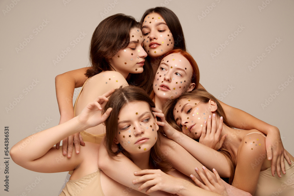Portrait of young beautiful women with nude makeup posing in beige underwear isolated over grey background. Togetherness Portrait of young beautiful women with nude makeup posing in beige underwear isolated over grey background. Togetherness