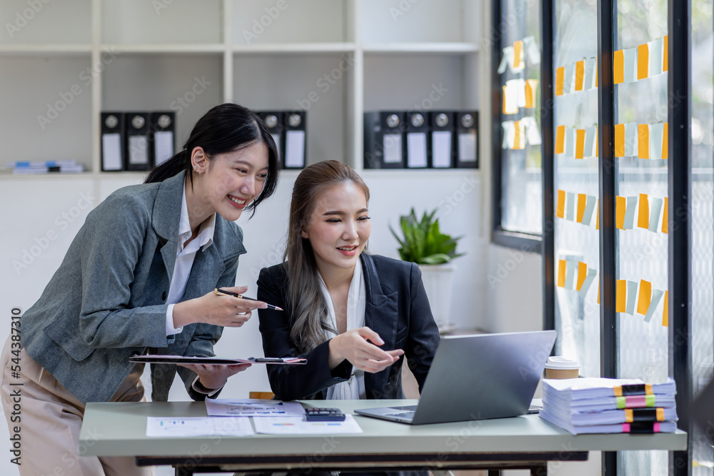 Two young asia business woman working together in office space, doing planning analyzing the financial report, business plan investment, finance analysis concept.