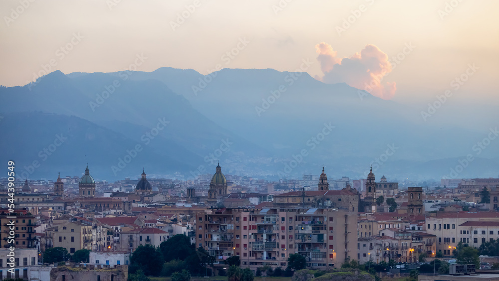 Residential Homes and Historic Church Buildings with mountains in background in Palermo, Sicily, Italy. Sunny Sunset Sky.