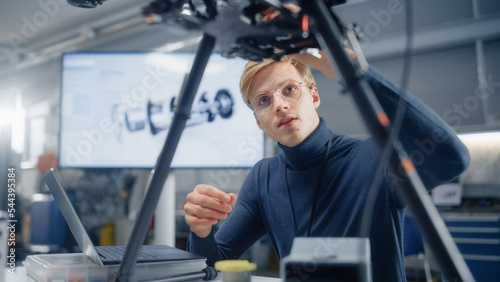 Young Caucasian Male Engineer Installs Processor in the Drone and Types on Laptop. Designing Unmanned Aerial Vehicle in Modern Laboratory. Technological Breakthrough in Aviation Concept.