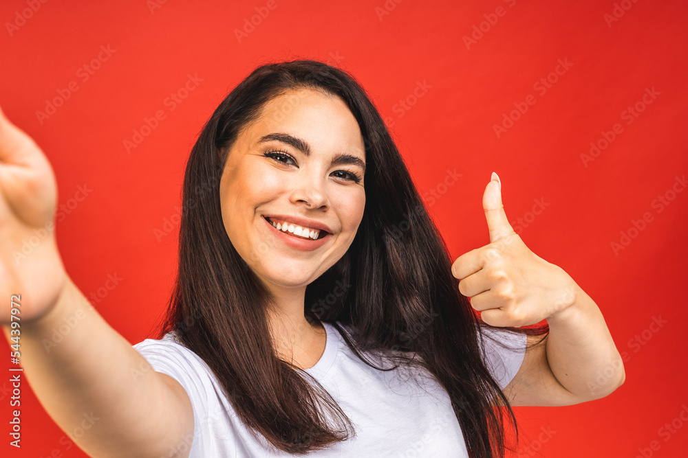 Portrait of pretty young happy woman making selfie on smartphone, isolated over red background. Portrait of pretty young happy woman making selfie on smartphone, isolated over red background.