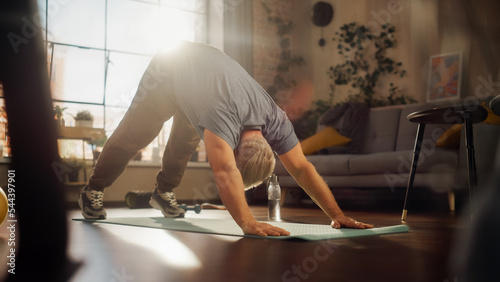 Strong Athletic Fit Middle Aged Man Training on a Yoga Mat, Doing Back Stretching and Core Strengthening Exercises During Morning Workout at Home in Sunny Apartment. Concept of Health and Fitness.