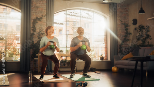 Obraz na plátně Happy Senior Couple Doing Morning Exercises and Kettlebell Workout Together at Home in Sunny Living Room