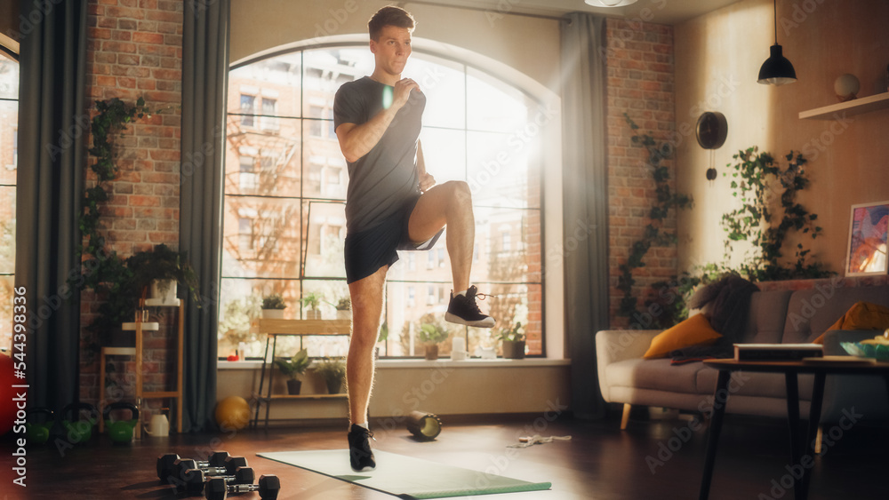 Strong Athletic Fit Young Man Doing Cardio High Knees and Core Strengthening Exercises During Morning Workout at Home in Sunny Apartment. Fitness and Recreation Concept. Stock Photo Adobe Stock