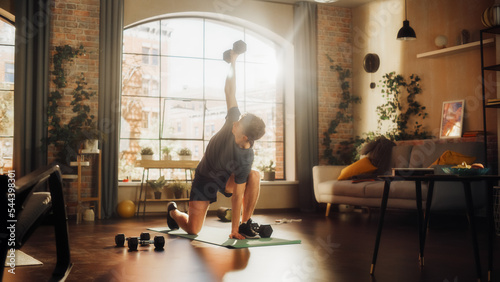 Strong Athletic Fit Young Man Training and Strengthening Arm Muscles with Dumbbell Exercises During Morning Workout at Home in Sunny Apartment. Concept of Healthy Lifestyle and Fitness.