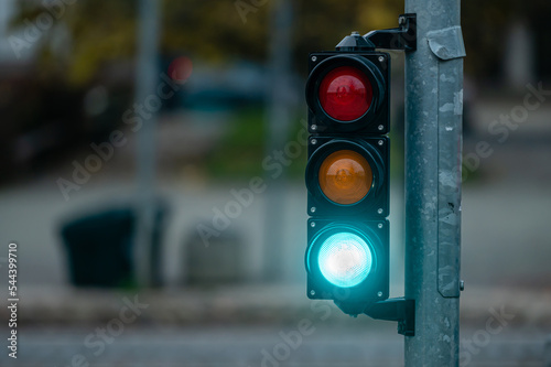 view of city traffic with traffic lights, in the foreground a semaphore with a green light, closeup