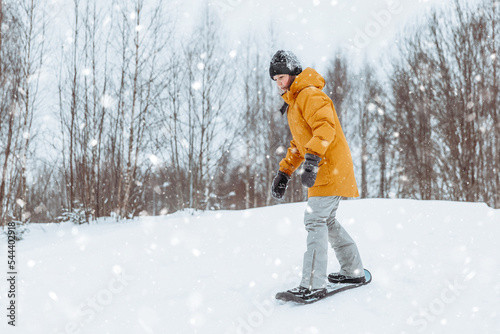 Cute teenage girl rides a snowskate in a winter park, healthy lifestyle