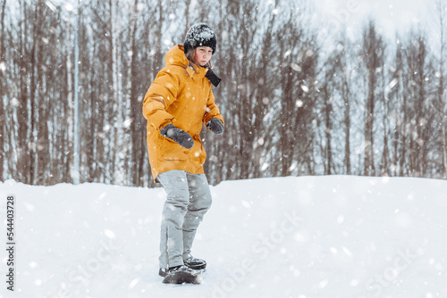 Cute teenage girl rides a snowskate in a winter park, healthy lifestyle photo