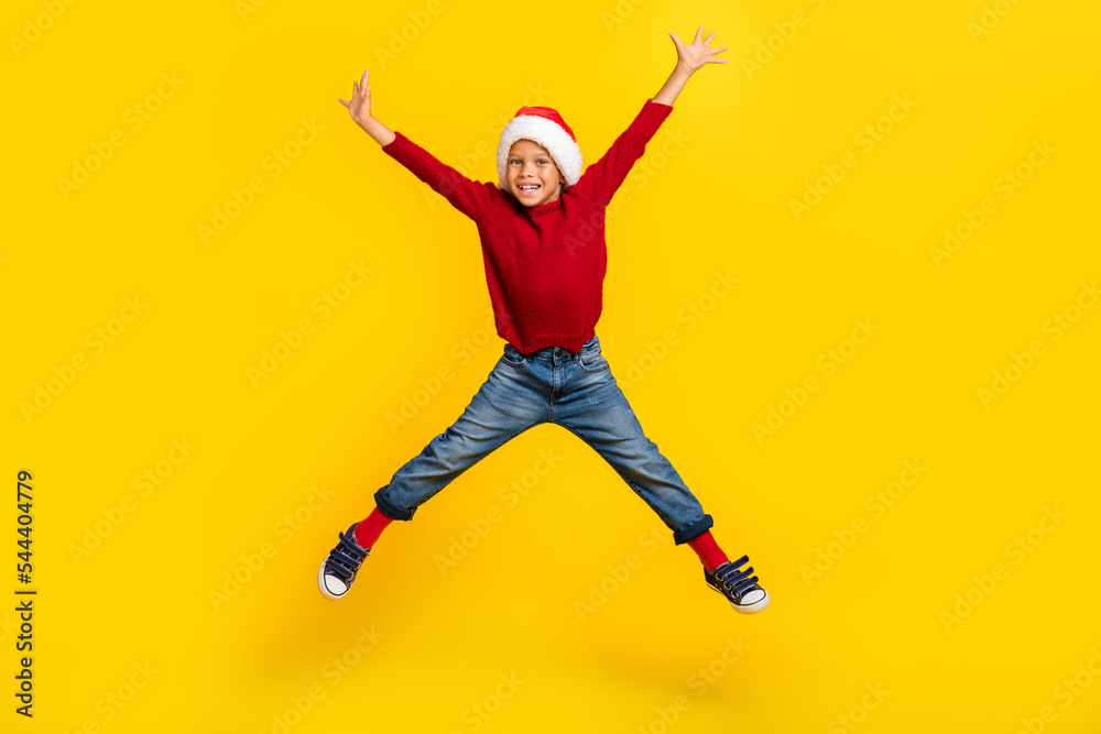 Full length photo of cute little boy jump high spread legs excited wait new year wear trendy red outfit isolated on yellow color background