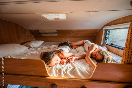 Fototapeta Kids are sleeping in alcove motorhome on road trip vacations.