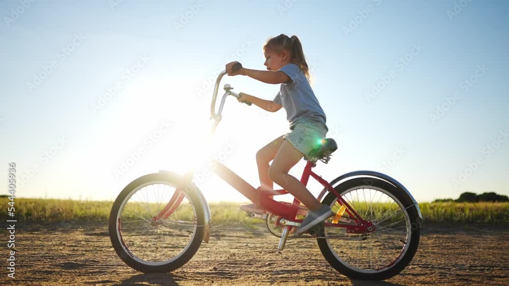 kid bike riding on a park. kid girl rides a bike in nature in the park on the road. happy family kid dream concept. daughter plays a bike rides on a sandy lifestyle road kid bike riding on a park. kid girl rides a bike in nature in the park on the road. happy family kid dream concept. daughter plays a bike rides on a sandy lifestyle road