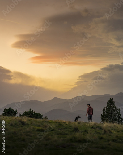 Atardecer con persona y perro sobre montañas con niebla photo