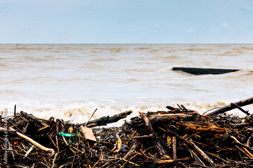 The sea coast after the storm. Plastic and wood waste on the beach pollute the environment. An environmental problem