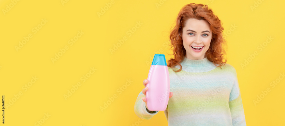 happy redhead woman with curly hair offering shampoo or conditioner, body care. Woman isolated face portrait, banner with copy space. happy redhead woman with curly hair offering shampoo or conditioner, body care. Woman isolated face portrait, banner with copy space.