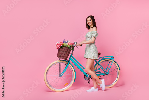 Full size photo of cute lady ride bicycle wear dress isolated on pink color background © deagreez