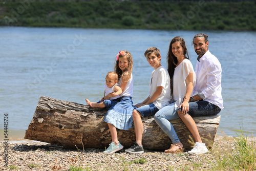 Glückliche Familie auf Baumstamm am Fluss