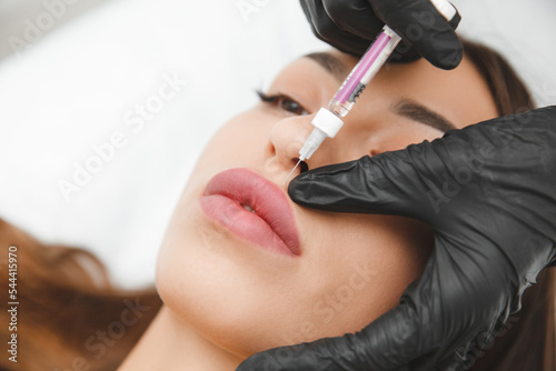 female lips, lip augmentation procedure. A syringe near a woman's mouth, injections to increase the shape of the lips