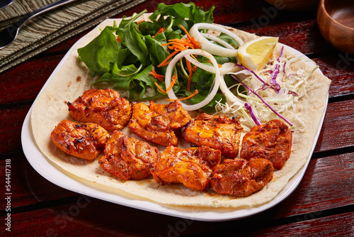 Spicy Sheesh Tawook or shish tikka boti kebab with salad, lemon and bread served in dish isolated on table side view of middle east food photo