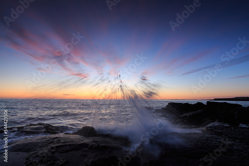 Fotobehang Rocky shore of the Atlantic Ocean at high tide at sunset