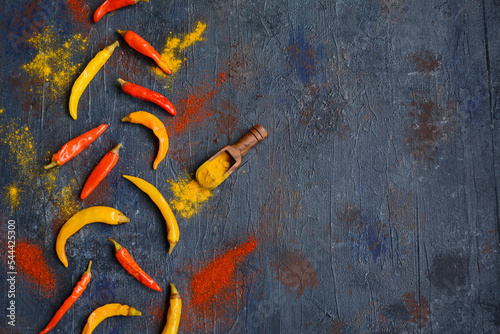 A layout of red and yellow hot chili peppers on a dark blue background. Top view, copy space