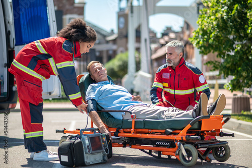 Female paramedic providing preparing an unconscious man for electrocardiography photo