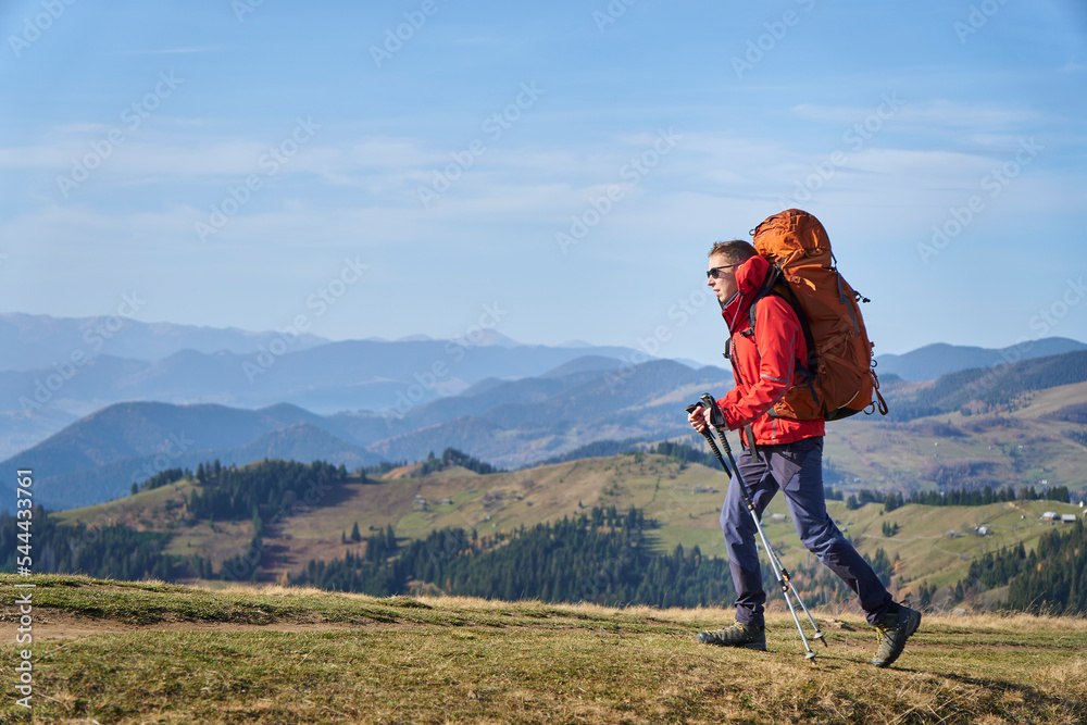 Young sporty hiker hiking in the mountains with his backpack on a bright sunny day. Picturesque mountain landscape.Concept of traveling in the mountains. Hiking in the mountains with a backpack Young sporty hiker hiking in the mountains with his backpack on a bright sunny day. Picturesque mountain landscape.Concept of traveling in the mountains. Hiking in the mountains with a backpack