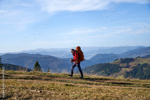 Young sporty hiker hiking in the mountains with his backpack on a bright sunny day. Picturesque mountain landscape.Concept of traveling in the mountains. Hiking in the mountains with a backpack 
