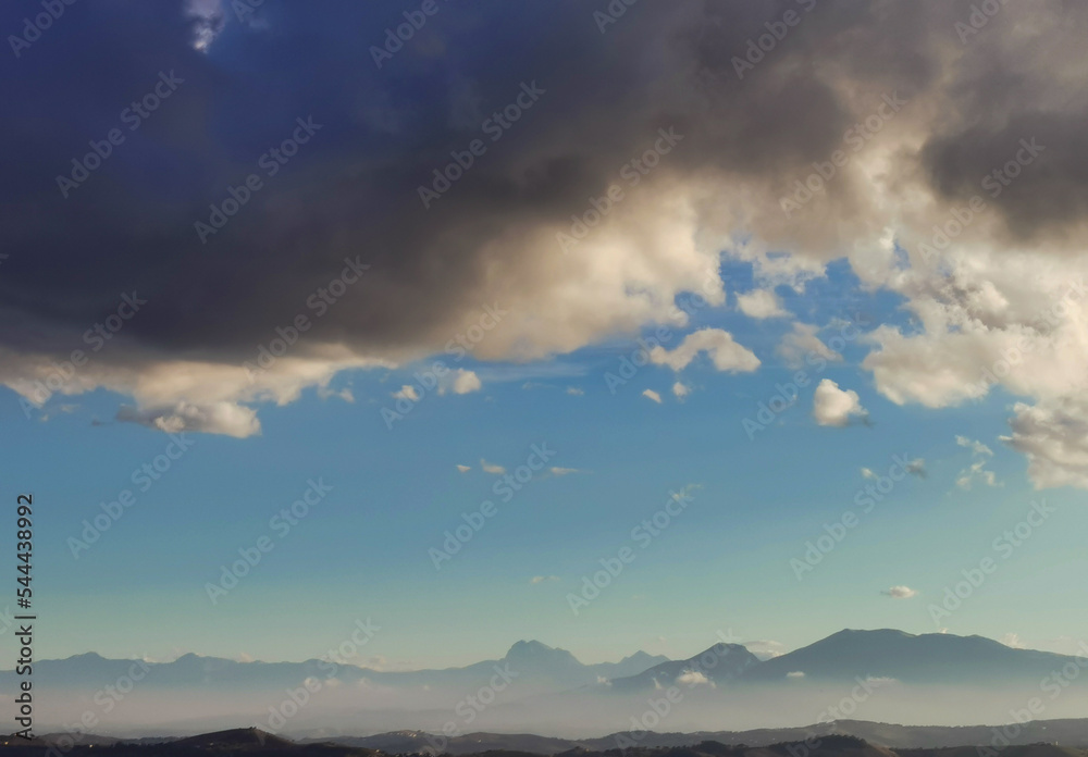 Nuvole bianche e nuvole nere nel cielo azzurro sopra i monti Appennini Nuvole bianche e nuvole nere nel cielo azzurro sopra i monti Appennini