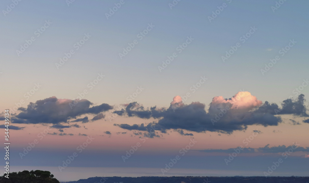 Nuvole sopra il mare e le colline nel cielo rosa del tramonto