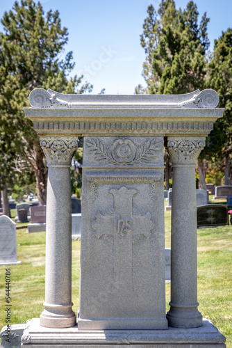 Religious Stone Headstone With Columns and a Cross at a Cemetery
