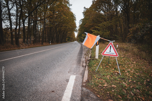 on the side of the road there is a sign with a flag with the warning Treibjagd