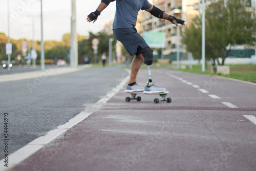Caucasian man with disability riding skateboard in park. Close-up of person with prosthetic leg on skateboard. Sport, disability, hobby concept