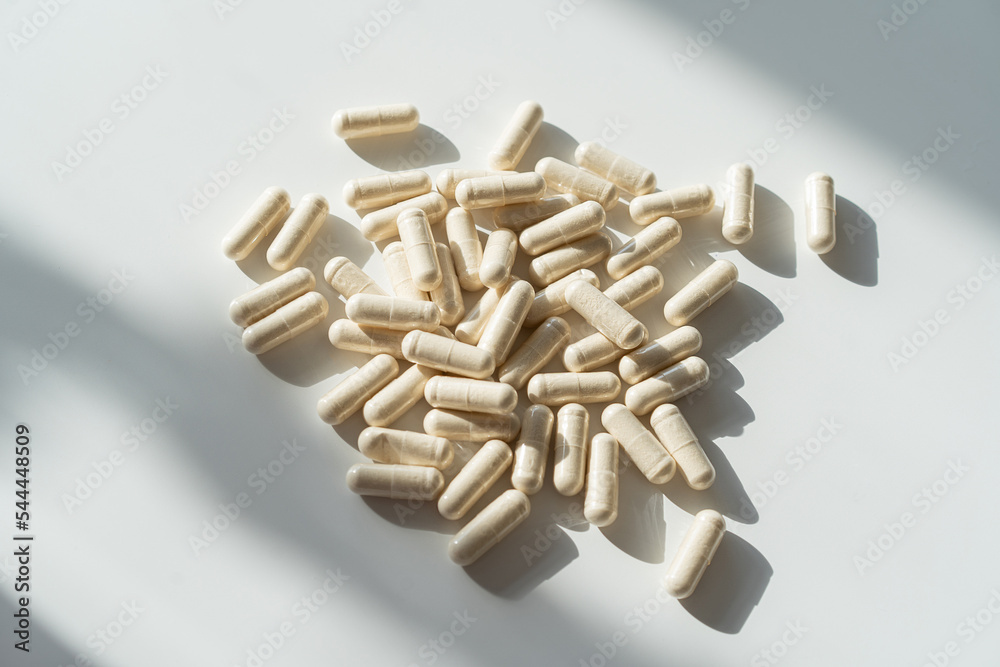 Vitamins on a white background. Pill capsules on a white background. Closeup of a pile of white medicine capsules. Top view.