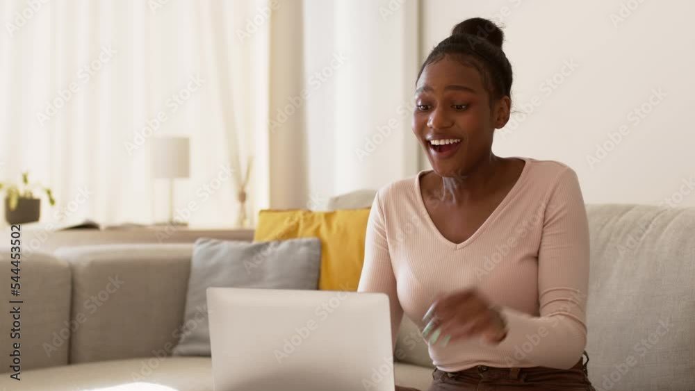 Young happy woman reading promotion letter on laptop and enjoying win, laughing at home, tracking shot, empty space Young happy woman reading promotion letter on laptop and enjoying win, laughing at home, tracking shot, empty space