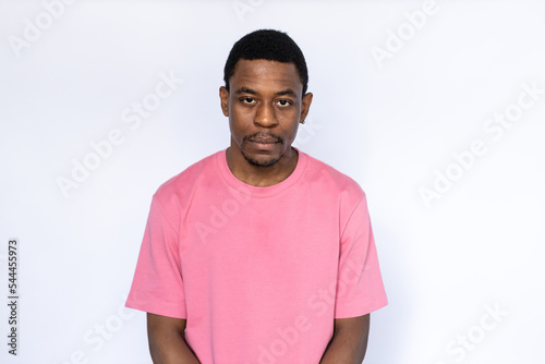 Portrait of serious African American man. Bored young male model with short dark hair in pink T-shirt looking at camera, unimpressed. Boredom, indifference concept
