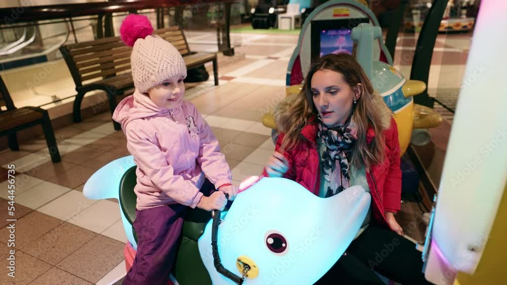 Mom is paying for a carousel for her daughter in mall