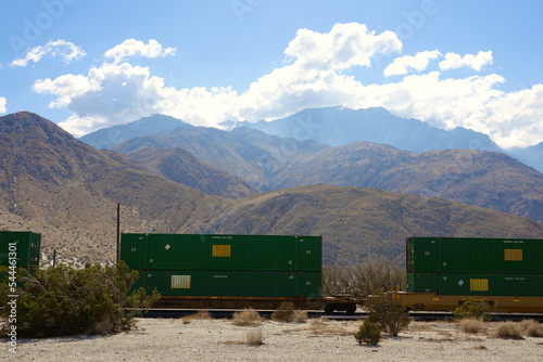 freight train moving stacked boxcars across the Mojave desert