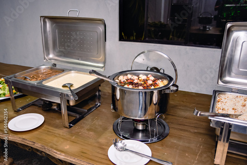 a stainless steel pan with cod served on the dinner table and a rice cooker