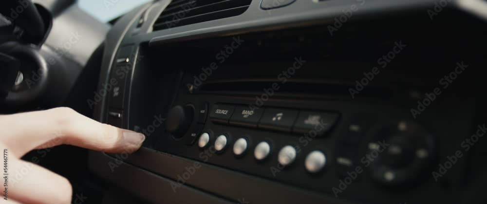 Hand adjusts sets press radio buttons female drives a car in close up Hand adjusts sets press radio buttons female drives a car in close up
