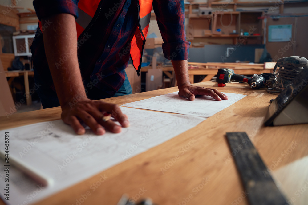 Close-up of mid adult man working next to digital tablet and tools in woodworking factory Close-up of mid adult man working next to digital tablet and tools in woodworking factory