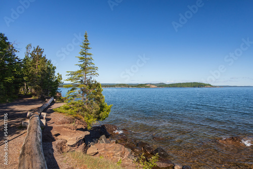 Fototapeta Naklejka Na Ścianę i Meble -  Trees on rocks and gravel beach, coastline of Lake Superior, Michigan