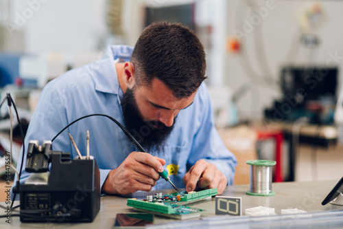 Electronics engineer working in a workshop with tin soldering parts photo