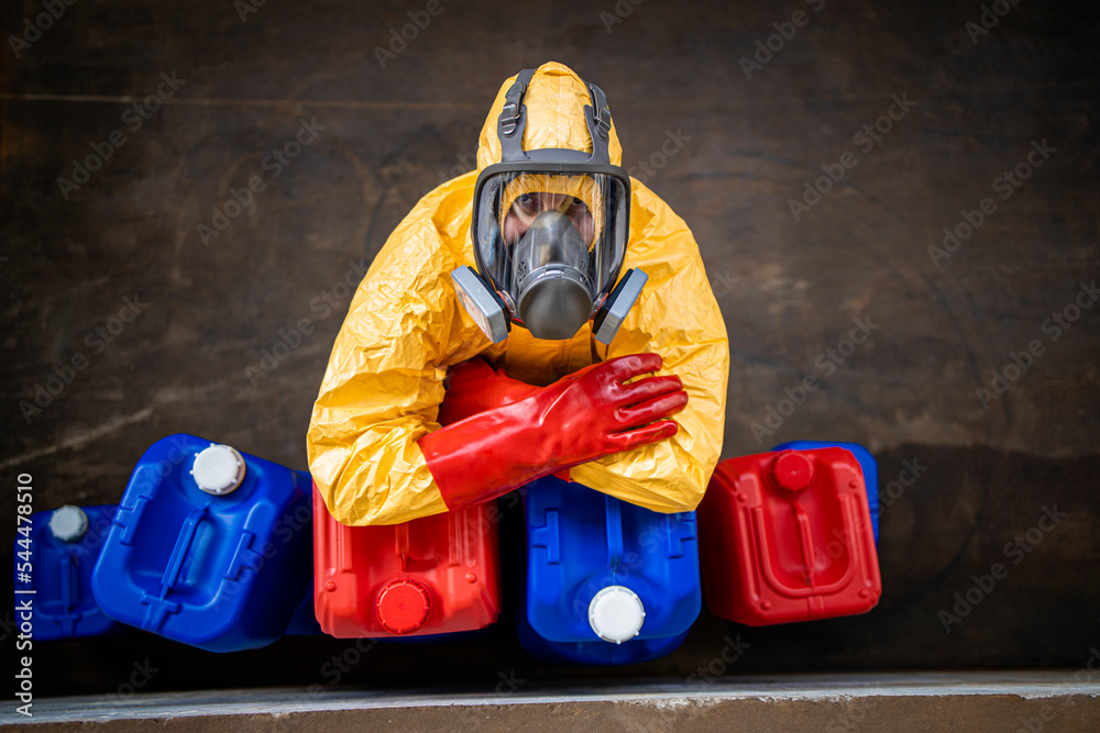 Foto Stock Top view of chemical worker wearing protective hazmat suit and  gas mask while leaning on plastic canisters inside chemicals production  plant. | Adobe Stock