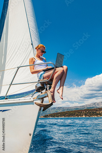 Woman with the laptop on the stem of the sailboat photo