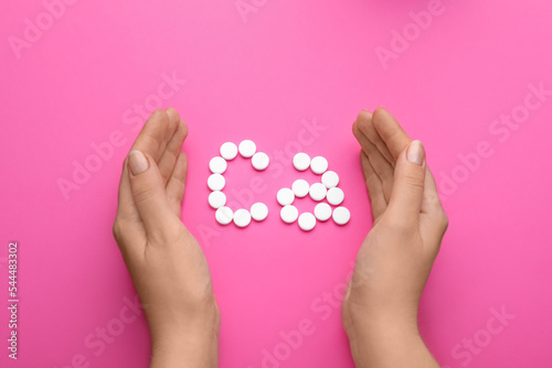 Woman with calcium symbol made of white pills on pink background, top view