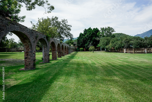 Arcos de acueducto de hacienda colonial antigua en verano con árboles